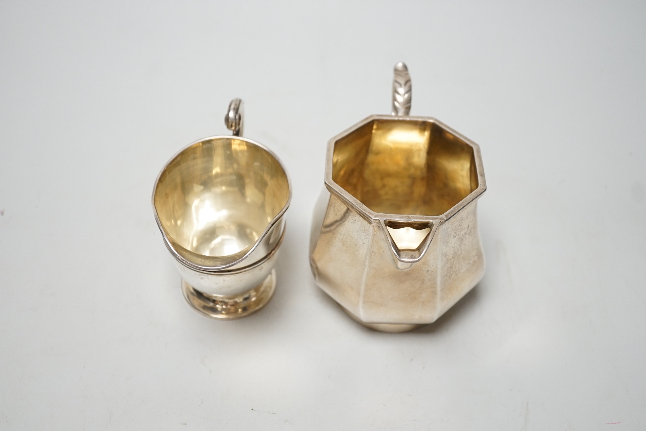 A George V panelled silver cream jug, by Elkington & Co, Birmingham, 1926, height 10cm and a late Victorian silver cream jug, London, 1899, 12.6oz.